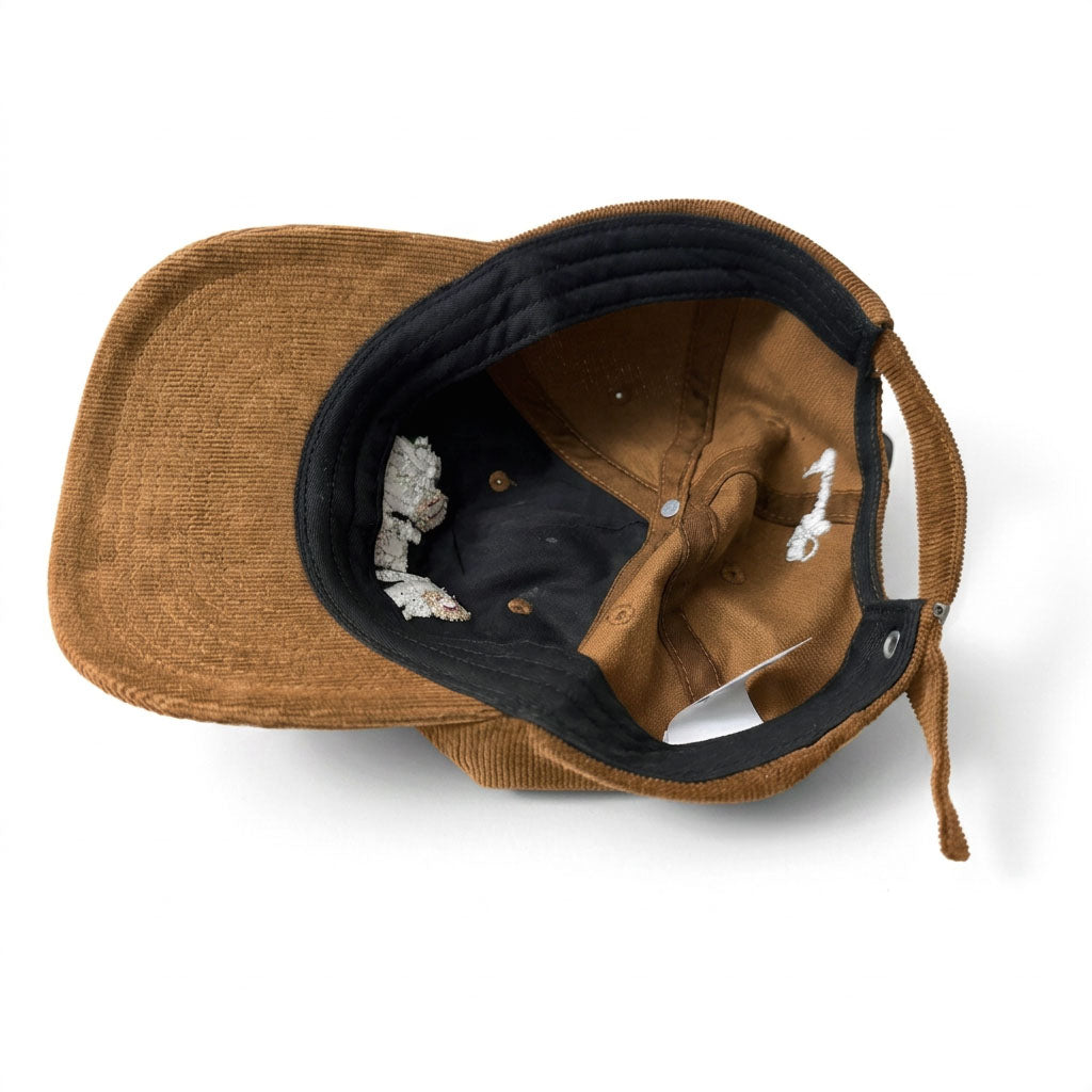 A brown corduroy baseball cap with a black interior lining, shown from an overhead angle on a white background.